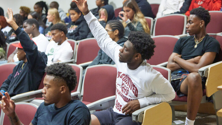 Student raising hand in a lecture hall at Shaw University