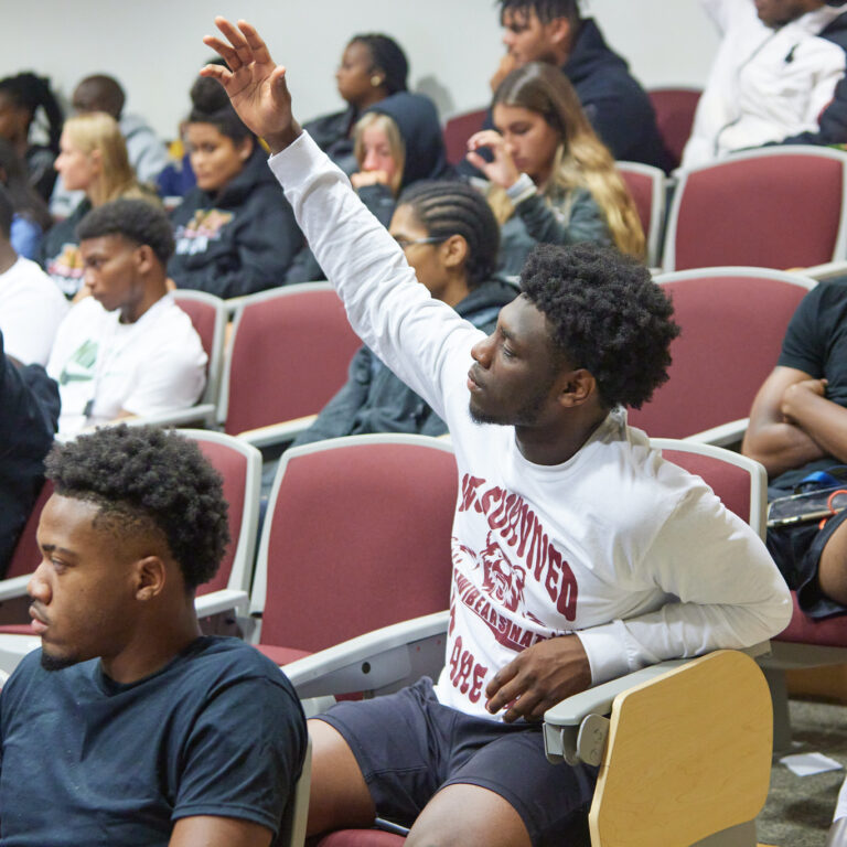 Student raising hand in a lecture hall at Shaw University